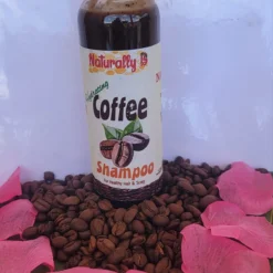 Naturally B coffee shampoo standing on coffee beans surrounded by flower petals